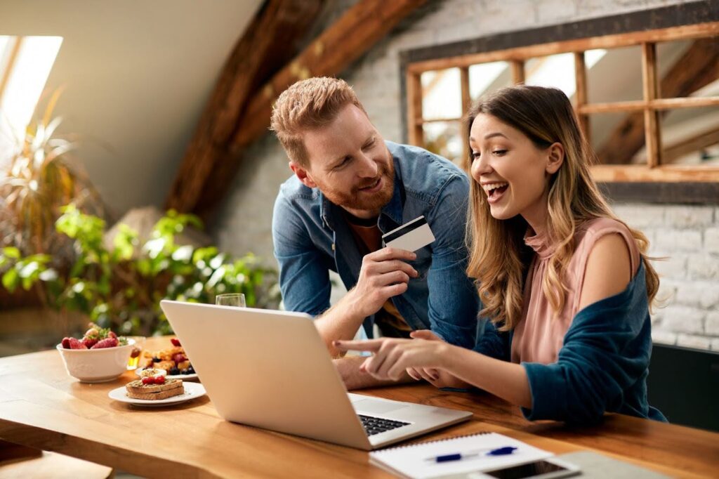 A man and woman are purchasing items online using a credit card, illustrating ecommerce online experience.