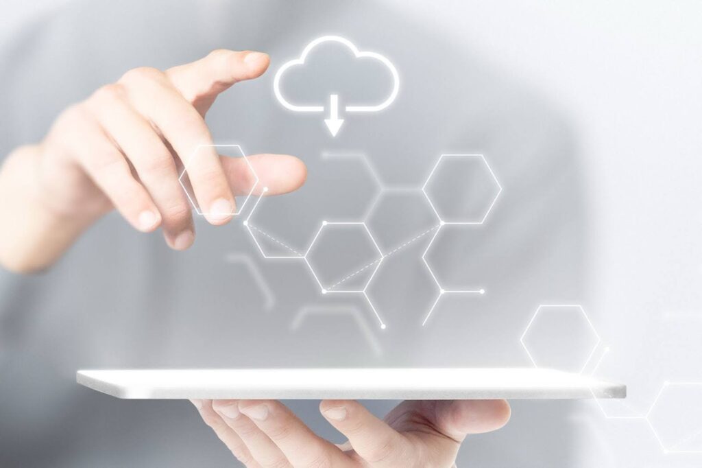 A person interacting with a floating tablet interface showing cloud icons and a hexagonal network, symbolizing futuristic cloud application development and cost considerations.