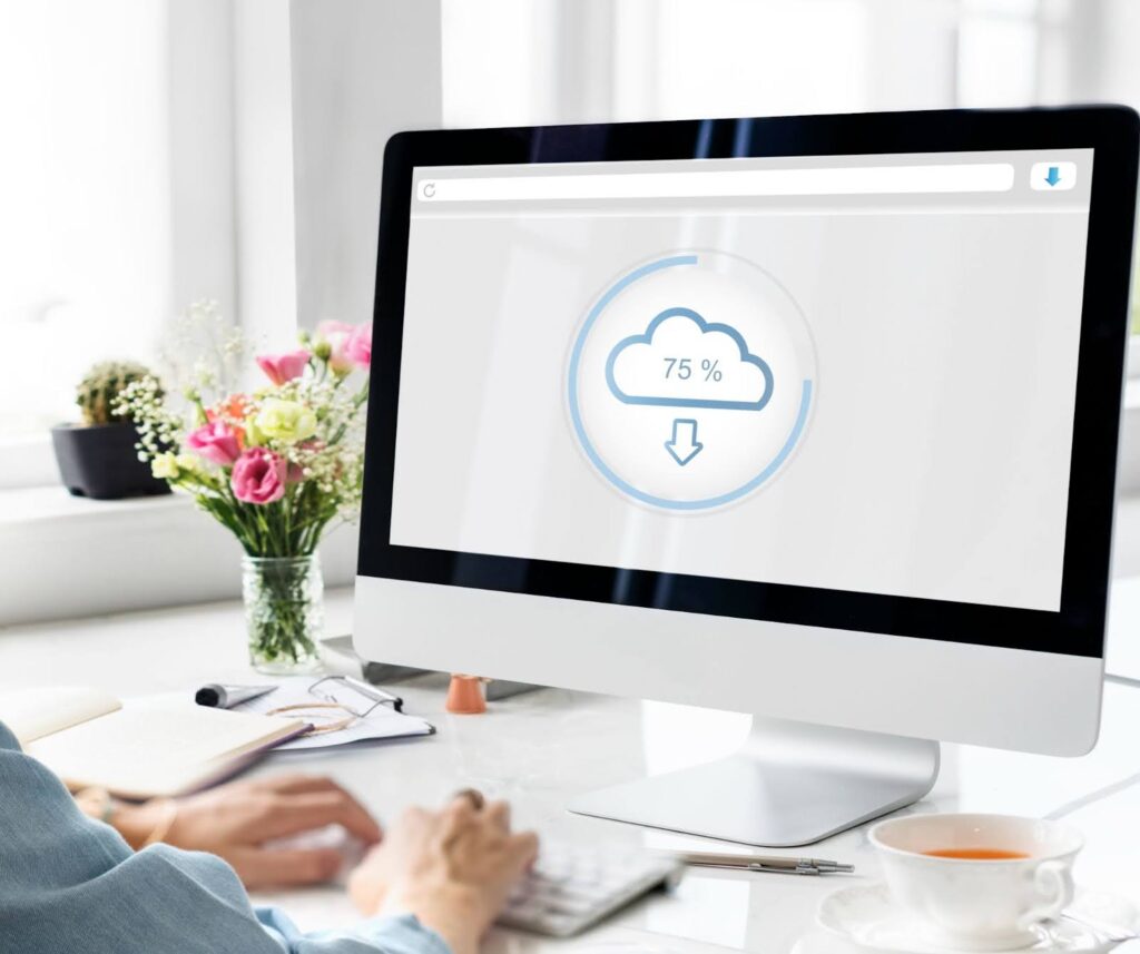 Computer screen showing cloud data upload progress in an office setup, representing cloud application development and related app development cost factors.
